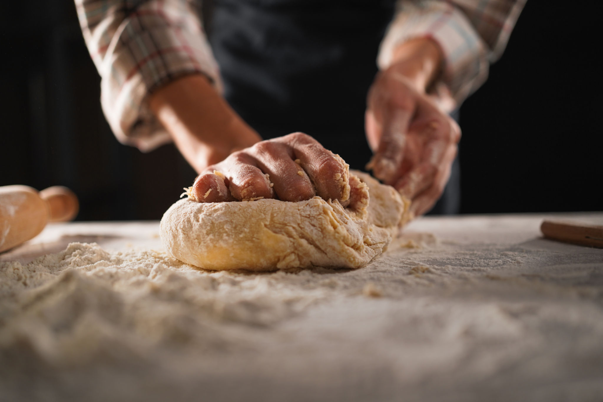 Baking concept: unrecognizable female prepares pastry, kneads dough on wooden table