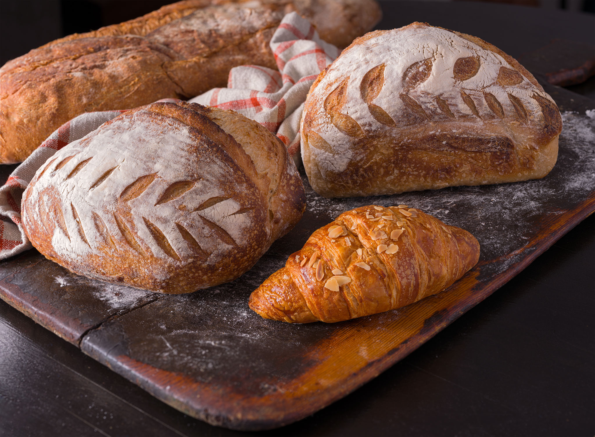Two loaves of sourdough bread and an almond croissant